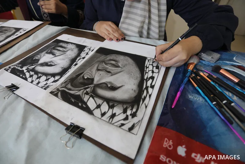 Palestinian graduates participate in a competition to draw the portrait of the death of late president Yasser Arafat, in Gaza city on November 211, 2021. Photo by Ashraf Amra