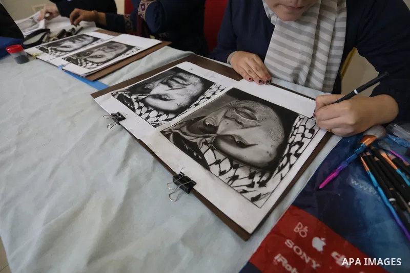 Palestinian graduates participate in a competition to draw the portrait of the death of late president Yasser Arafat, in Gaza city on November 211, 2021. Photo by Ashraf Amra