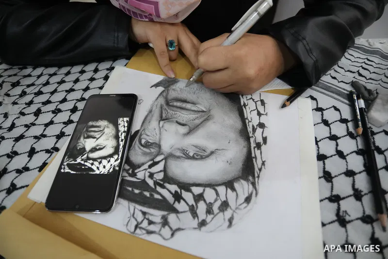 Palestinian graduates participate in a competition to draw the portrait of the death of late president Yasser Arafat, in Gaza city on November 211, 2021. Photo by Ashraf Amra