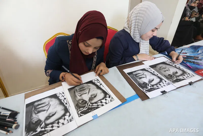 Palestinian graduates participate in a competition to draw the portrait of the death of late president Yasser Arafat, in Gaza city on November 211, 2021. Photo by Ashraf Amra