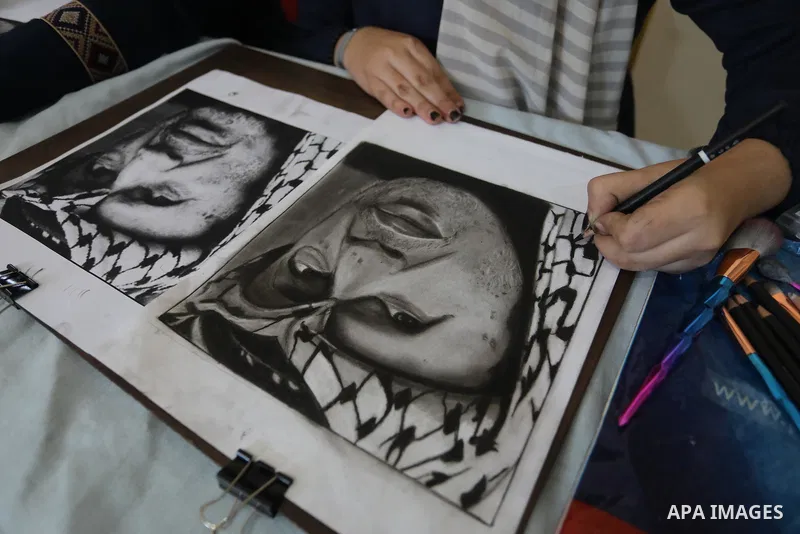 Palestinian graduates participate in a competition to draw the portrait of the death of late president Yasser Arafat, in Gaza city on November 211, 2021. Photo by Ashraf Amra
