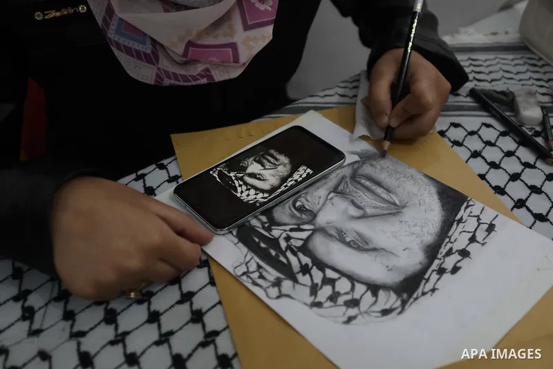 Palestinian graduates participate in a competition to draw the portrait of the death of late president Yasser Arafat, in Gaza city on November 211, 2021. Photo by Ashraf Amra
