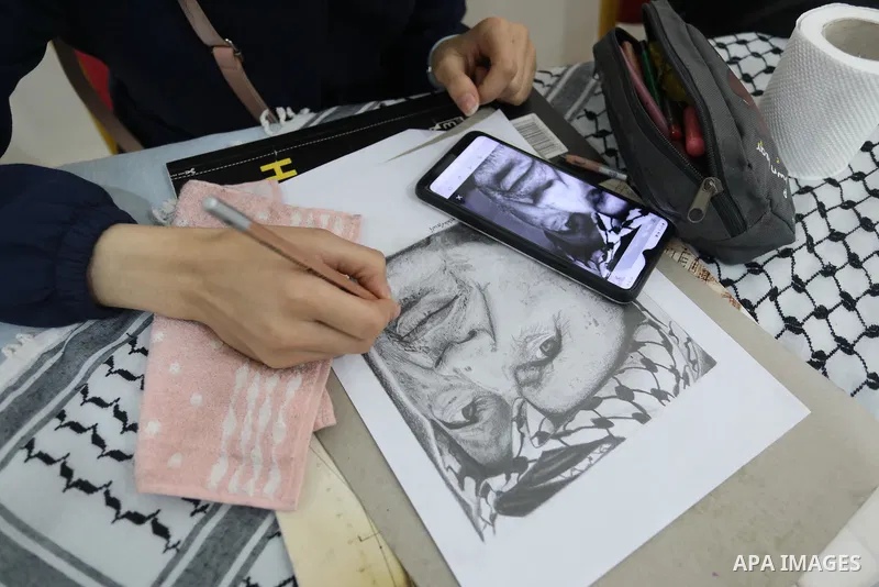 Palestinian graduates participate in a competition to draw the portrait of the death of late president Yasser Arafat, in Gaza city on November 211, 2021. Photo by Ashraf Amra