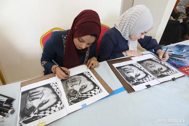 Palestinian graduates participate in a competition to draw the portrait of the death of late president Yasser Arafat, in Gaza city on November 211, 2021. Photo by Ashraf Amra