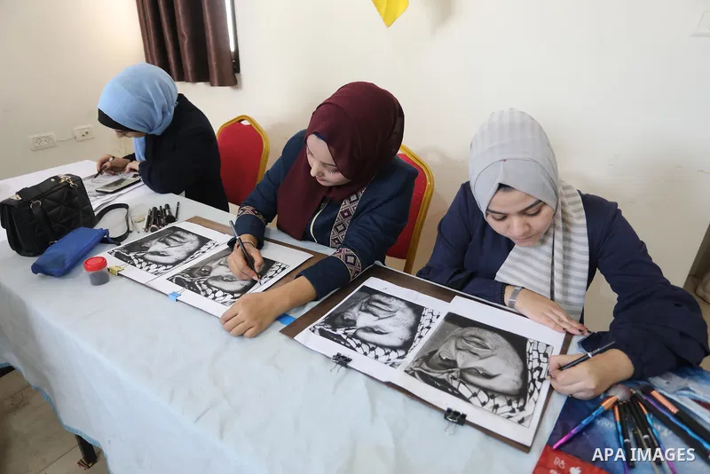Palestinian graduates participate in a competition to draw the portrait of the death of late president Yasser Arafat, in Gaza city on November 211, 2021. Photo by Ashraf Amra
