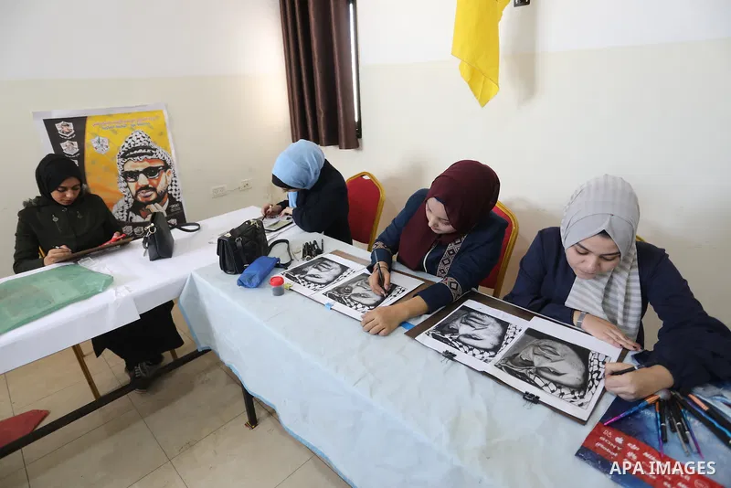 Palestinian graduates participate in a competition to draw the portrait of the death of late president Yasser Arafat, in Gaza city on November 211, 2021. Photo by Ashraf Amra