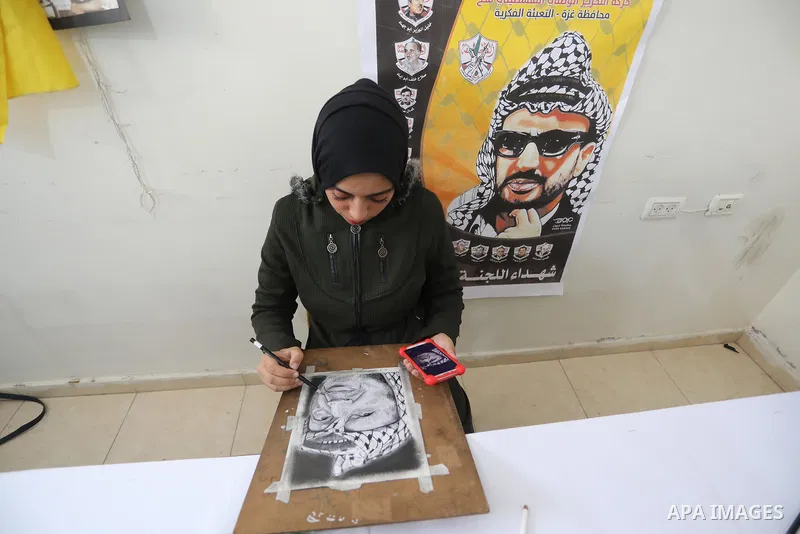 Palestinian graduates participate in a competition to draw the portrait of the death of late president Yasser Arafat, in Gaza city on November 211, 2021. Photo by Ashraf Amra