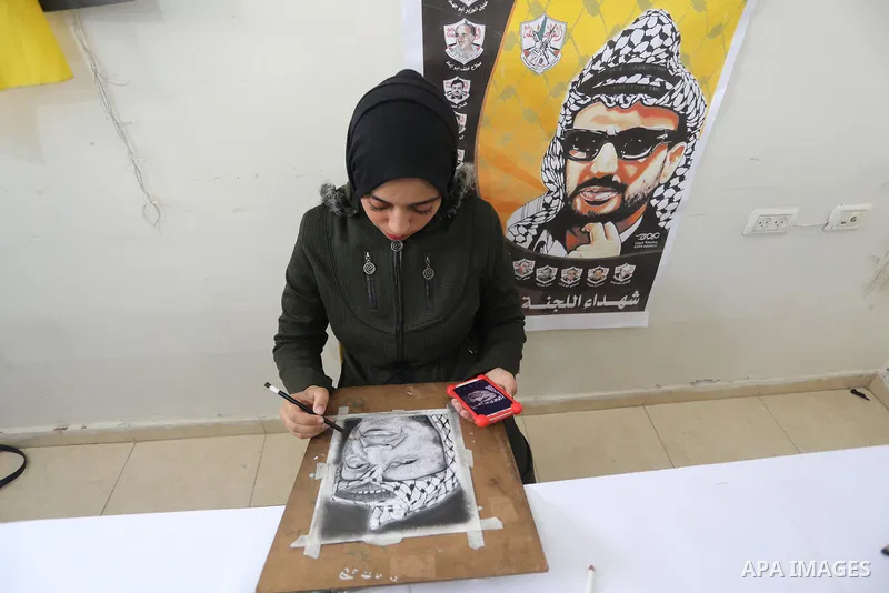Palestinian graduates participate in a competition to draw the portrait of the death of late president Yasser Arafat, in Gaza city on November 211, 2021. Photo by Ashraf Amra