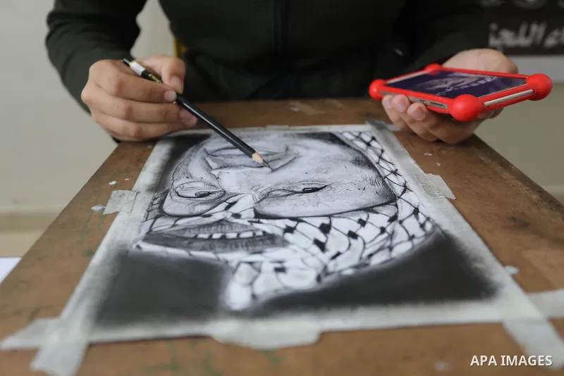 Palestinian graduates participate in a competition to draw the portrait of the death of late president Yasser Arafat, in Gaza city on November 211, 2021. Photo by Ashraf Amra