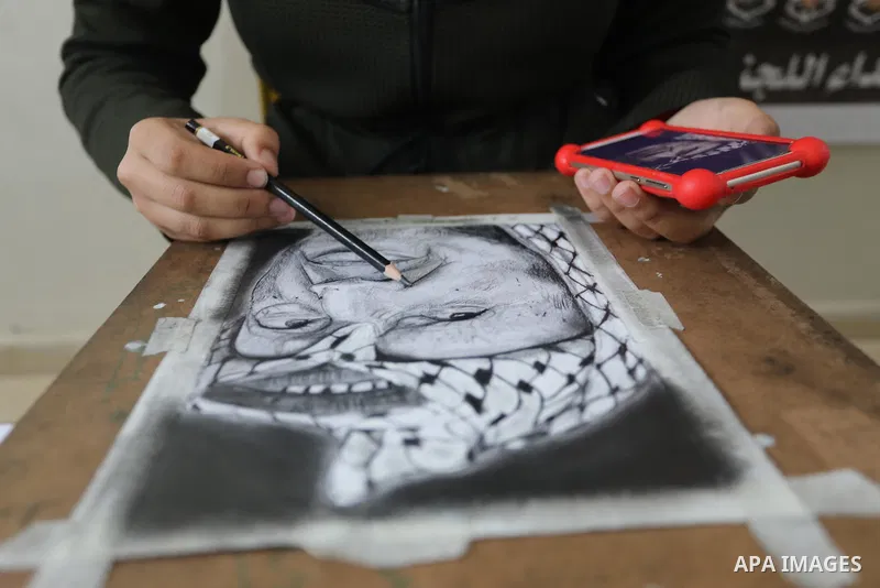 Palestinian graduates participate in a competition to draw the portrait of the death of late president Yasser Arafat, in Gaza city on November 211, 2021. Photo by Ashraf Amra