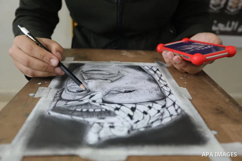 Palestinian graduates participate in a competition to draw the portrait of the death of late president Yasser Arafat, in Gaza city on November 211, 2021. Photo by Ashraf Amra