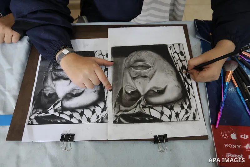 Palestinian graduates participate in a competition to draw the portrait of the death of late president Yasser Arafat, in Gaza city on November 211, 2021. Photo by Ashraf Amra