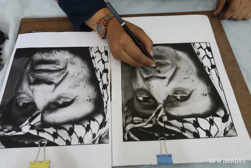 Palestinian graduates participate in a competition to draw the portrait of the death of late president Yasser Arafat, in Gaza city on November 211, 2021. Photo by Ashraf Amra