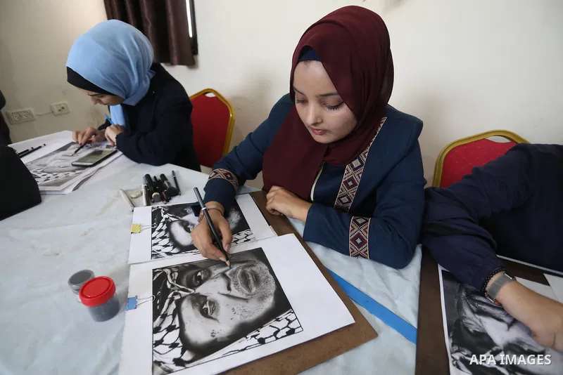 Palestinian graduates participate in a competition to draw the portrait of the death of late president Yasser Arafat, in Gaza city on November 211, 2021. Photo by Ashraf Amra