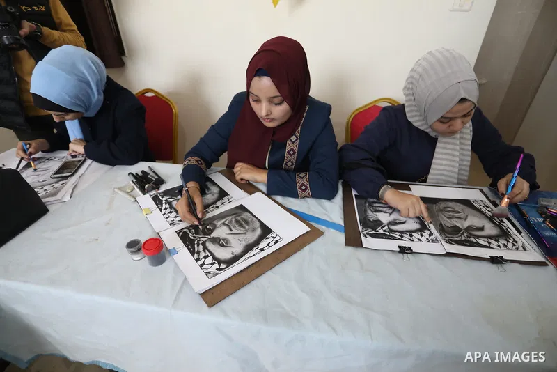 Palestinian graduates participate in a competition to draw the portrait of the death of late president Yasser Arafat, in Gaza city on November 211, 2021. Photo by Ashraf Amra