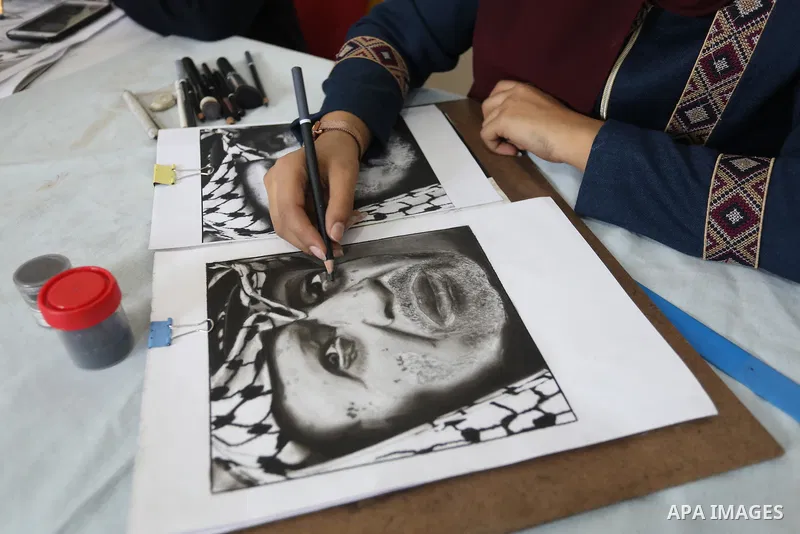 Palestinian graduates participate in a competition to draw the portrait of the death of late president Yasser Arafat, in Gaza city on November 211, 2021. Photo by Ashraf Amra