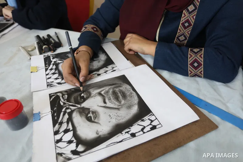 Palestinian graduates participate in a competition to draw the portrait of the death of late president Yasser Arafat, in Gaza city on November 211, 2021. Photo by Ashraf Amra