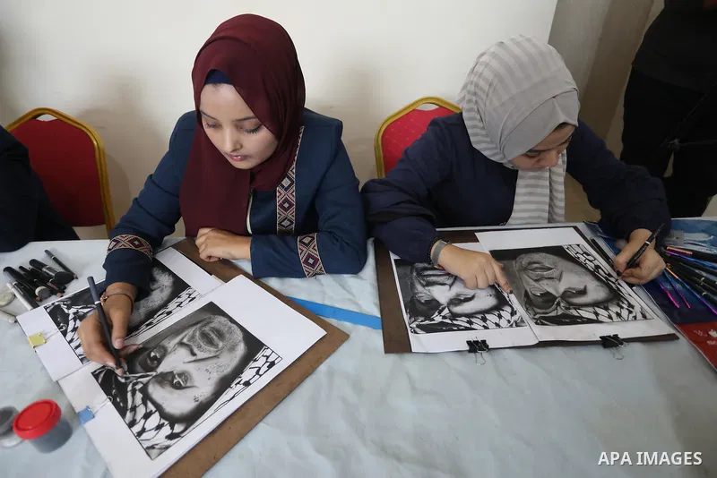 Palestinian graduates participate in a competition to draw the portrait of the death of late president Yasser Arafat, in Gaza city on November 211, 2021. Photo by Ashraf Amra
