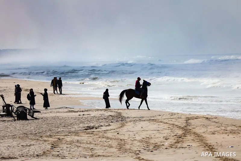Palestians enjoy during a coldy day, at a beach in Gaza City 21 November 2021. The effects of the low pressure front which affected Palestine yesterday are expected to remain on Sunday, with a slight rise in temperature...