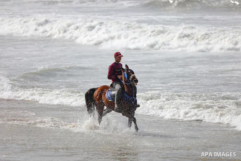 Palestians enjoy during a coldy day, at a beach in Gaza City 21 November 2021. The effects of the low pressure front which affected Palestine yesterday are expected to remain on Sunday, with a slight rise in temperature...