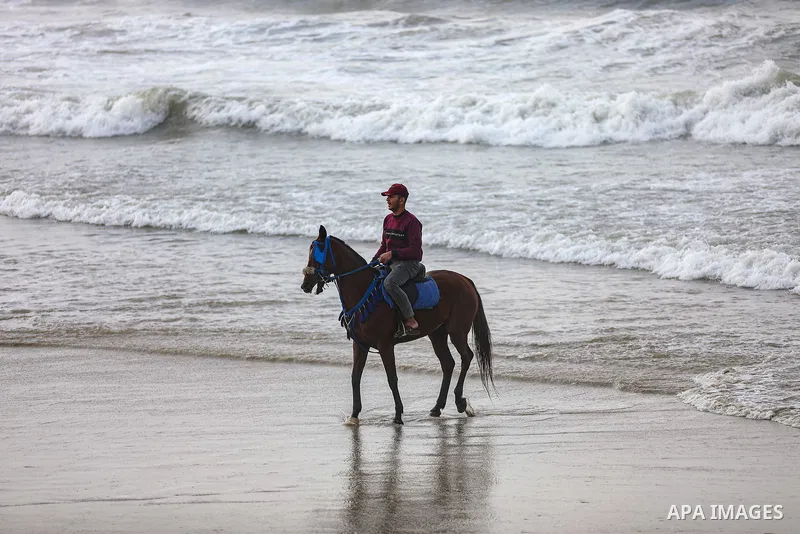 Palestians enjoy during a coldy day, at a beach in Gaza City 21 November 2021. The effects of the low pressure front which affected Palestine yesterday are expected to remain on Sunday, with a slight rise in temperature...