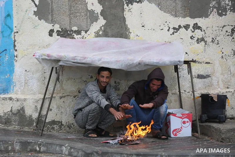 Palestinians show as they in their daily lives during a rainy day, in Deir al-Balah in the center of Gaza strip on November 21, 2021. The effects of the low pressure front which affected Palestine yesterday are expected...