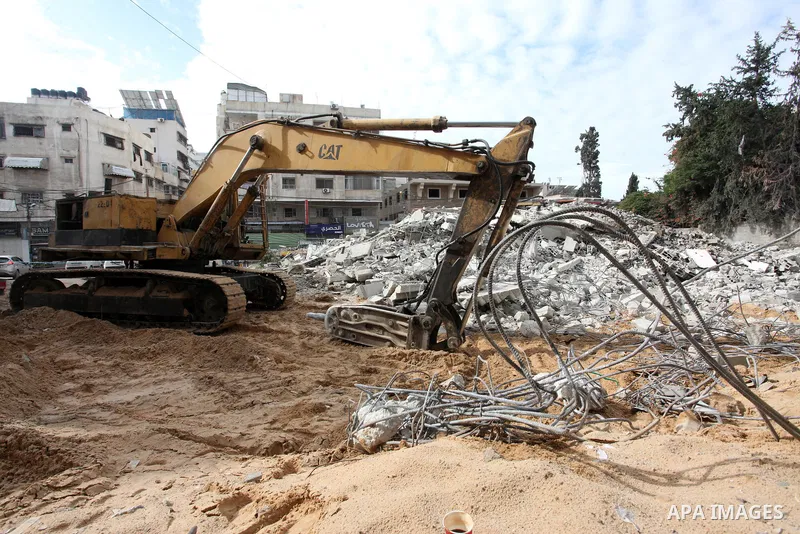 Palestinian workers use a bulldozer to remove the rubbles of a building which was hit by Israeli strikes during the recent 11-day conflict between Israel and Hamas on May, in Gaza city on November 22, 2021. Qatar and Egy...