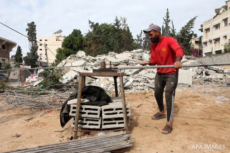 Palestinian workers remove the rubbles of a building which was hit by Israeli strikes during the recent 11-day conflict between Israel and Hamas on May, in Gaza city on November 22, 2021. Qatar and Egypt have signed agre...