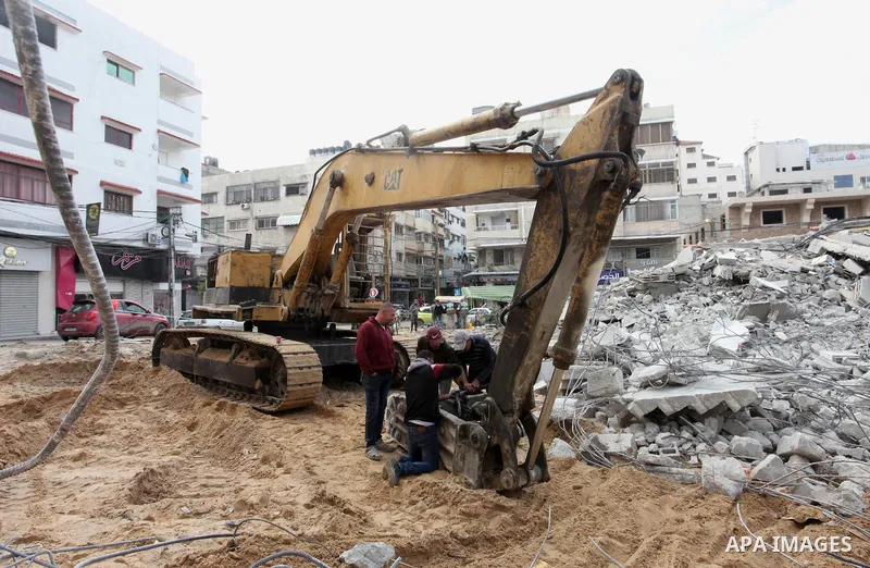 Palestinian workers use a bulldozer to remove the rubbles of a building which was hit by Israeli strikes during the recent 11-day conflict between Israel and Hamas on May, in Gaza city on November 22, 2021. Qatar and Egy...