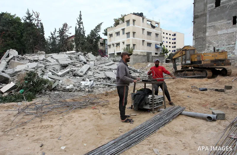 Palestinian workers remove the rubbles of a building which was hit by Israeli strikes during the recent 11-day conflict between Israel and Hamas on May, in Gaza city on November 22, 2021. Qatar and Egypt have signed agre...