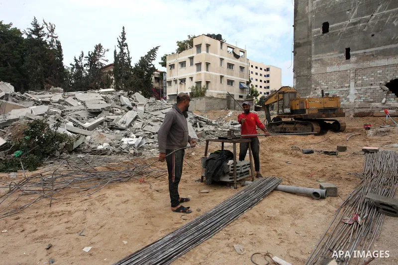 Palestinian workers remove the rubbles of a building which was hit by Israeli strikes during the recent 11-day conflict between Israel and Hamas on May, in Gaza city on November 22, 2021. Qatar and Egypt have signed agre...