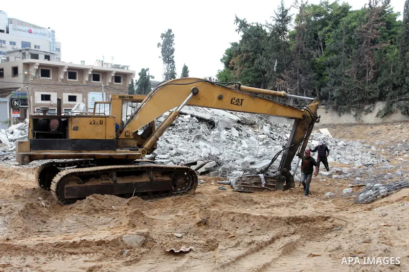 Palestinian workers use a bulldozer to remove the rubbles of a building which was hit by Israeli strikes during the recent 11-day conflict between Israel and Hamas on May, in Gaza city on November 22, 2021. Qatar and Egy...