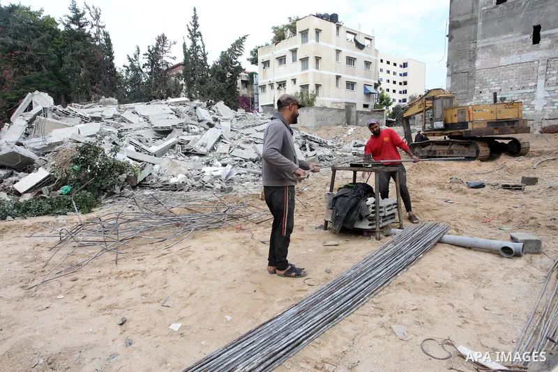 Palestinian workers remove the rubbles of a building which was hit by Israeli strikes during the recent 11-day conflict between Israel and Hamas on May, in Gaza city on November 22, 2021. Qatar and Egypt have signed agre...