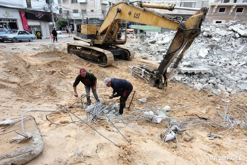 Palestinian workers use a bulldozer to remove the rubbles of a building which was hit by Israeli strikes during the recent 11-day conflict between Israel and Hamas on May, in Gaza city on November 22, 2021. Qatar and Egy...