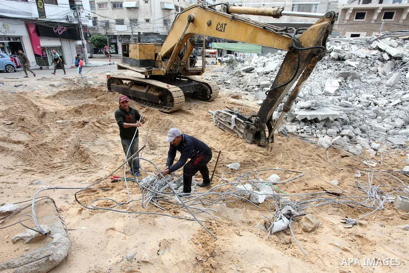 Palestinian workers use a bulldozer to remove the rubbles of a building which was hit by Israeli strikes during the recent 11-day conflict between Israel and Hamas on May, in Gaza city on November 22, 2021. Qatar and Egy...