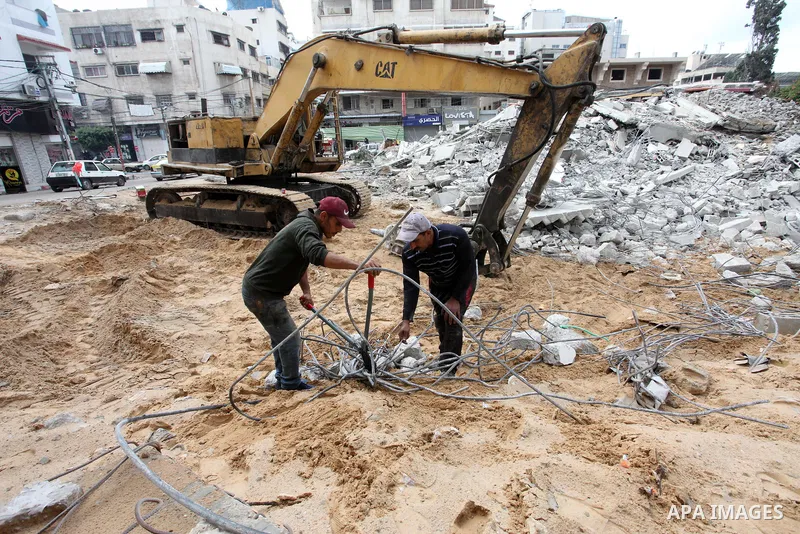 Palestinian workers use a bulldozer to remove the rubbles of a building which was hit by Israeli strikes during the recent 11-day conflict between Israel and Hamas on May, in Gaza city on November 22, 2021. Qatar and Egy...