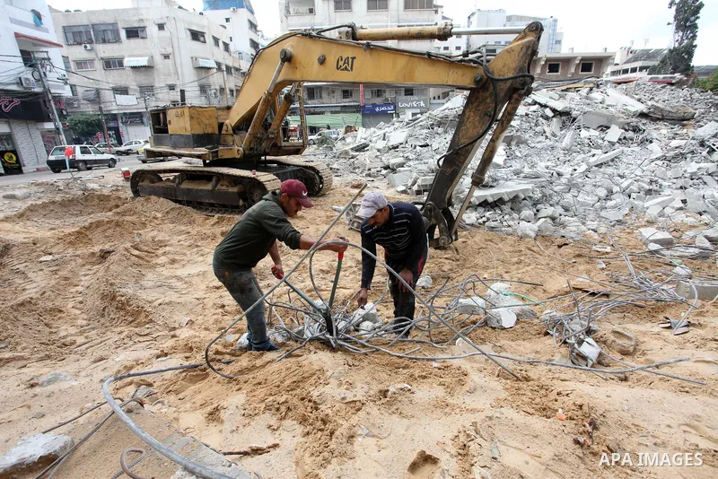 Palestinian workers use a bulldozer to remove the rubbles of a building which was hit by Israeli strikes during the recent 11-day conflict between Israel and Hamas on May, in Gaza city on November 22, 2021. Qatar and Egy...