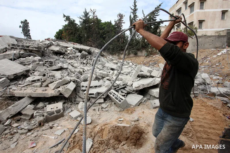 Palestinian workers remove the rubbles of a building which was hit by Israeli strikes during the recent 11-day conflict between Israel and Hamas on May, in Gaza city on November 22, 2021. Qatar and Egypt have signed agre...
