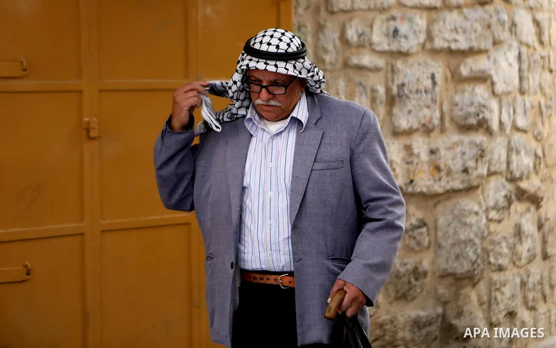 A Palestinian man wearing Keffiyeh walks at a street in the West Bank City of Hebron, on November 22, 2021. Keffiyeh is black-and-white chequered scarf is a traditional Arabian headdress. Photo by Mamoun Wazwaz