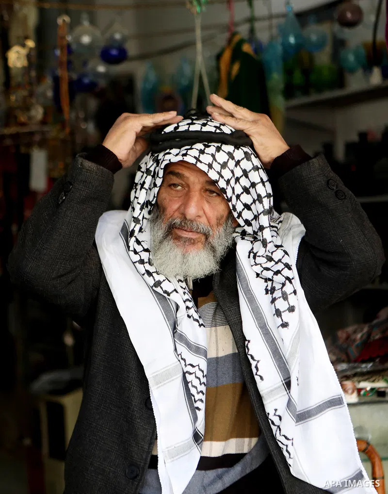 A Palestinian man wearing Keffiyeh walks at a street in the West Bank City of Hebron, on November 22, 2021. Keffiyeh is black-and-white chequered scarf is a traditional Arabian headdress. Photo by Mamoun Wazwaz