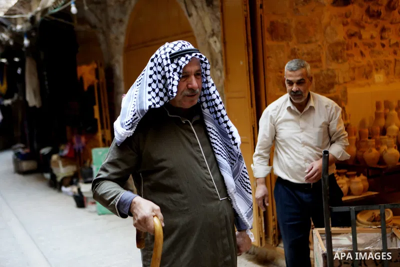 A Palestinian man wearing Keffiyeh walks at a street in the West Bank City of Hebron, on November 22, 2021. Keffiyeh is black-and-white chequered scarf is a traditional Arabian headdress. Photo by Mamoun Wazwaz