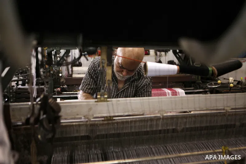 A Palestinian man works at a Keffiyeh textile factory in the West Bank City of Hebron, on November 22, 2021. Keffiyeh is black-and-white chequered scarf is a traditional Arabian headdress. Photo by Mamoun Wazwaz