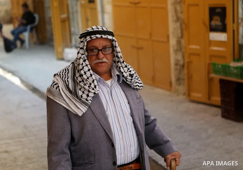 A Palestinian man wearing Keffiyeh walks at a street in the West Bank City of Hebron, on November 22, 2021. Keffiyeh is black-and-white chequered scarf is a traditional Arabian headdress. Photo by Mamoun Wazwaz