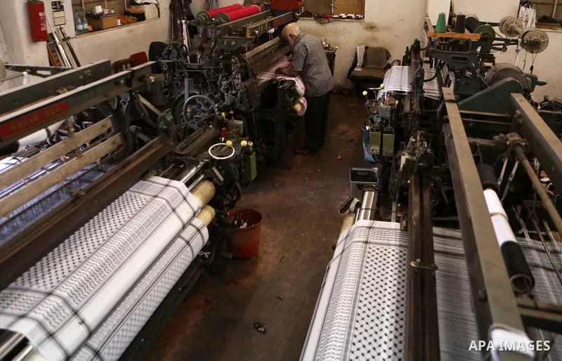A Palestinian man works at a Keffiyeh textile factory in the West Bank City of Hebron, on November 22, 2021. Keffiyeh is black-and-white chequered scarf is a traditional Arabian headdress. Photo by Mamoun Wazwaz
