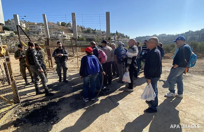 Palestinian farmers wait to enter to their lands that lie behind the separation wall to pick olives, in the West Bank city of Bethlehem on November 24, 2021. Photo by WAFA