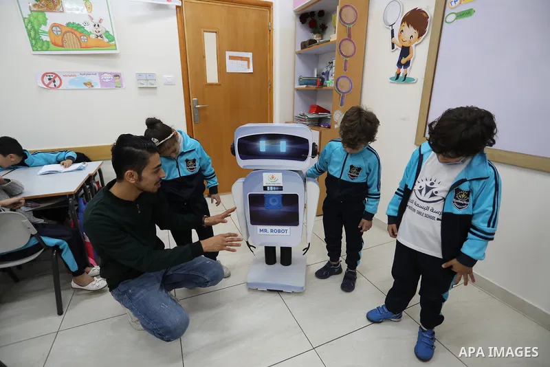 Palestinian students interact with a locally-made educational robot during a science class at a private school in Gaza City on November 30, 2021. Photo by Ashraf Amra