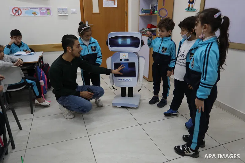 Palestinian students interact with a locally-made educational robot during a science class at a private school in Gaza City on November 30, 2021. Photo by Ashraf Amra