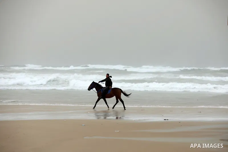 A Palestinian man reares his horse as he ride during stormy weather along a beach by the Mediterranean Sea in Gaza City on December 8, 2021. Photo by Ashraf Amra