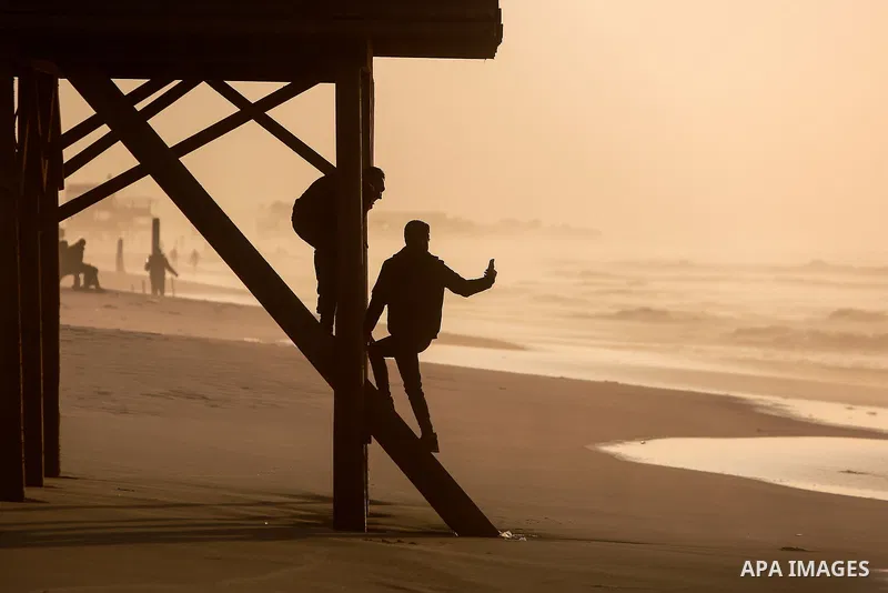 Palestinians walk during stormy weather along a beach by the Mediterranean Sea in Gaza City on December 9, 202. Photo by Mohammed Dahman