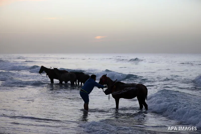 Palestinians enjoy their time during sunset along a beach by the Mediterranean Sea in Gaza City on December 10, 2021. Photo by Ashraf Amra